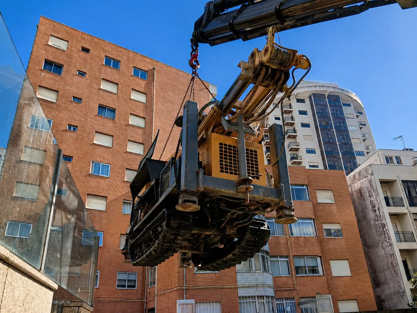Máquina de perfuração içada por grua numa obra urbana